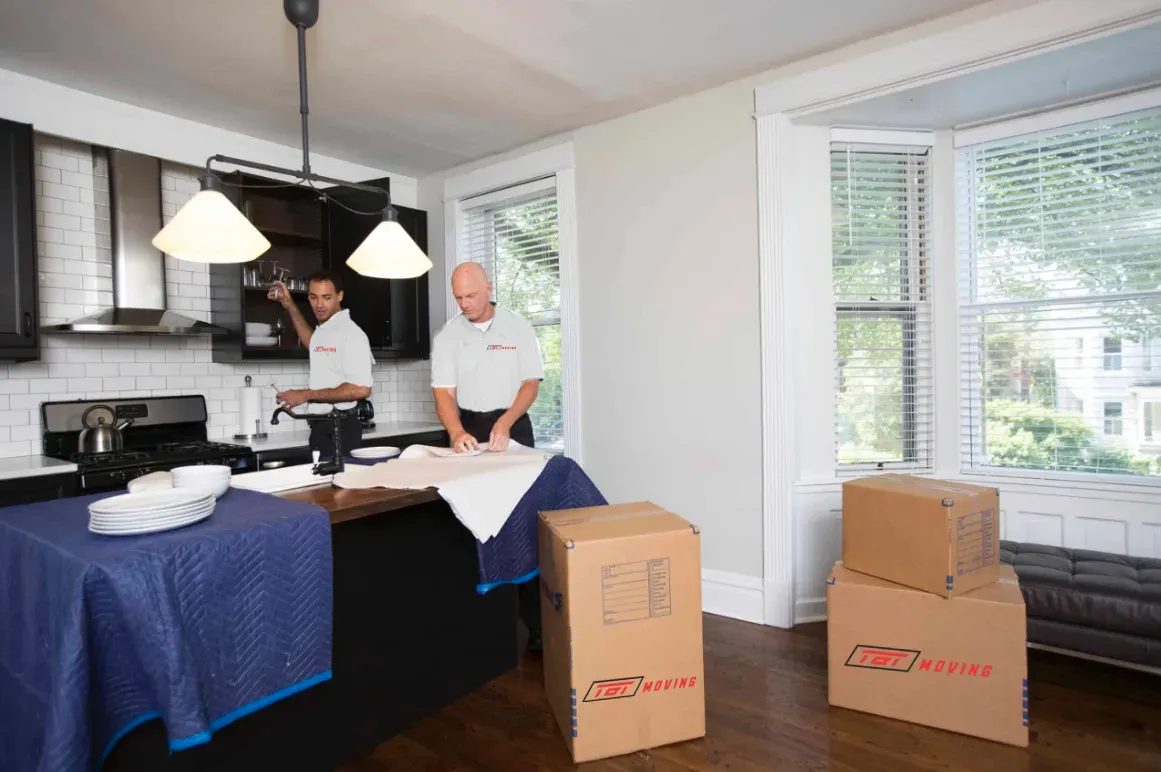 Movers wrapping a table in protective padding